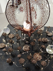 An abstract sculpture of crystalised rocks and crystal balls and netting, looking reminescent of coral with small fairy lights around the bottom.