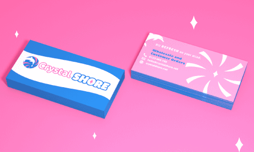 A mockup of business cards with the logo and dolphin graphic on the back. The business card front has a blue wave bordering the top and bottom with the logo Crystal Shore in the middle. The back is pink with a light swirl graphic, a dolphin graphic in the top left, and the logo tagline 'Hit refresh on your mind'. Wholesale and Customer Orders with a phone number, email, and web address.